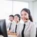 happy customer service call center representatives wearing their headsets and seated on their desks